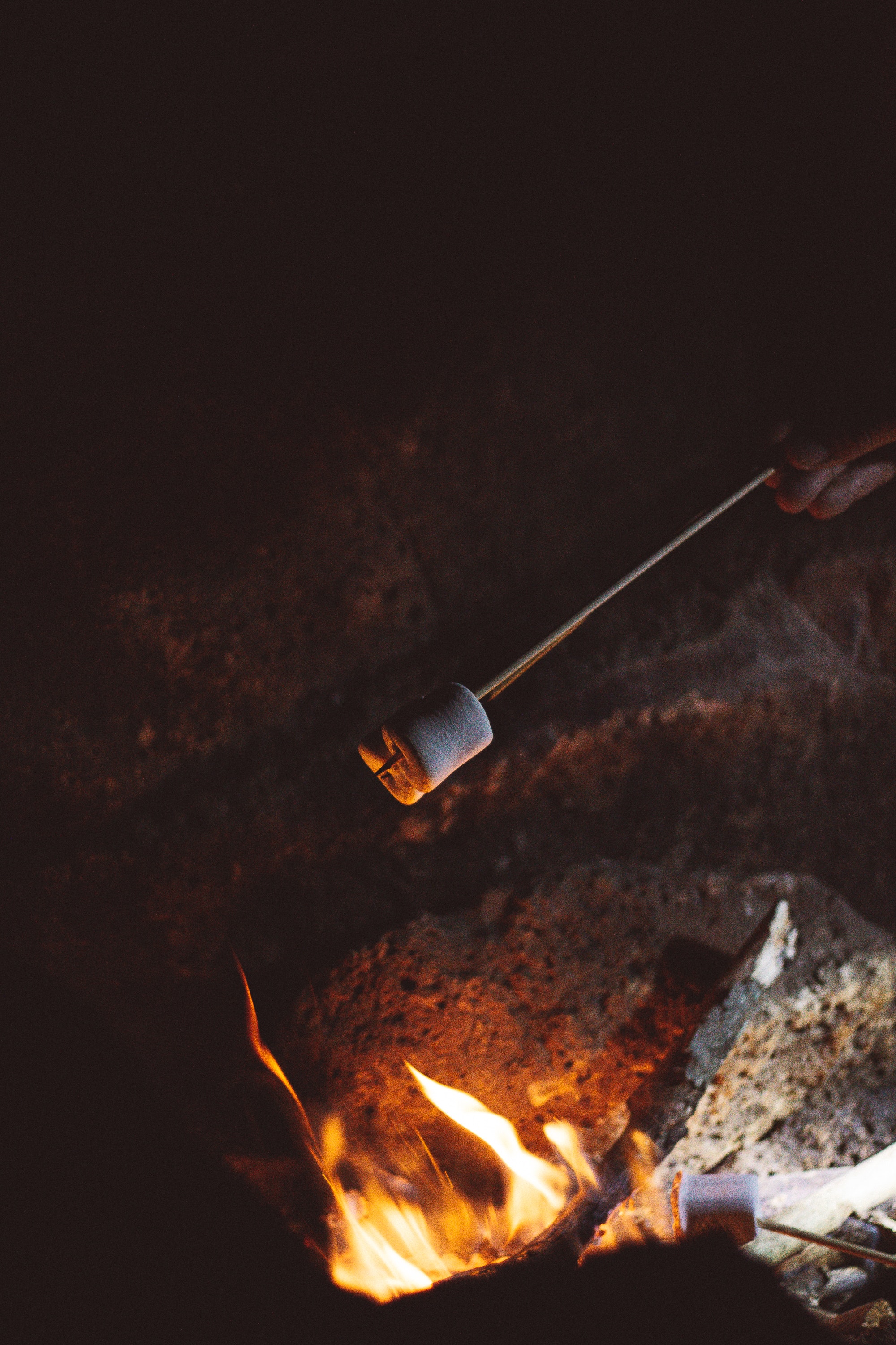 a marshmallow on a stick being roasted over a fire in the dark